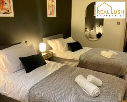 ein Hotelzimmer mit 2 Betten und einem Spiegel in der Unterkunft Real Lush Properties - East Street - Luxury Two-Bedroom Apartment In Leicester in Leicester