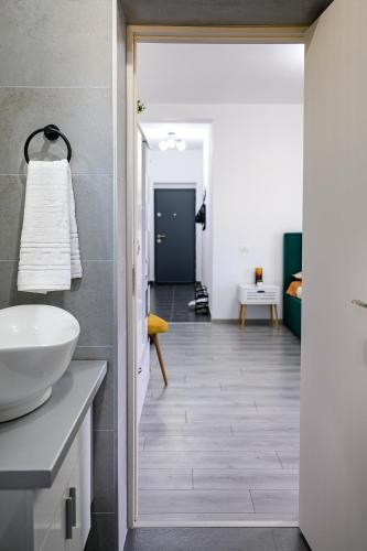 a bathroom with a white sink and a hallway at Natura Residence in Târgu Jiu