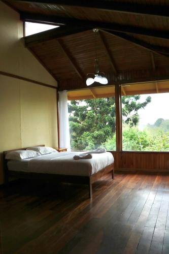 a bedroom with a bed and a large window at Poas Volcano & La Paz Waterfall Cabins in Montaña Azul