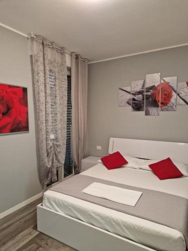 una camera da letto con un letto bianco con cuscini rossi di Appartamento Piccola Perla a Cologno Monzese