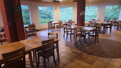 a restaurant with wooden tables and chairs and windows at Poas Volcano & La Paz Waterfall Cabins in Montaña Azul