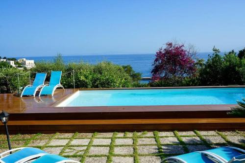 a swimming pool with chairs and the ocean in the background at Villa capri con giardino e piscina in Capri