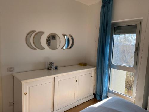 a bedroom with a white cabinet and mirrors on the wall at Trilocale luminoso immerso nella natura in Forte dei Marmi