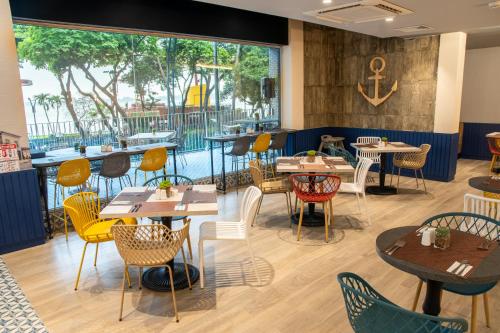 a restaurant with tables and chairs and a large window at Ibis Styles El Malecon Guayaquil in Guayaquil