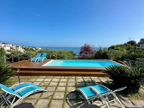 a swimming pool with two chairs and the ocean at Villa capri con giardino e piscina in Capri
