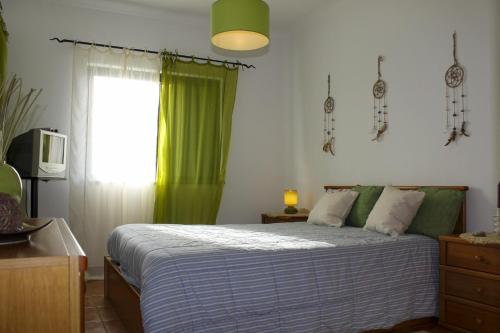 1 dormitorio con 1 cama con cortina verde y ventana en Condominio Vilita, T1-Lt-5,F Pera-Silves en Pêra