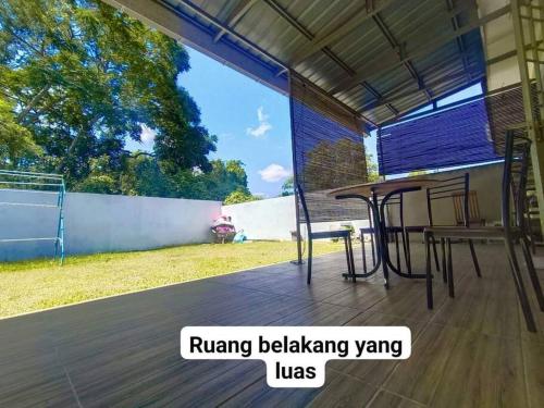a patio with a table and chairs on a wooden floor at Hmsty D Hutan Kampung Alor Setar (Muslim) 