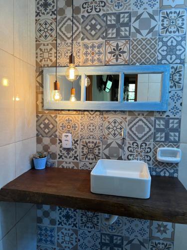 a bathroom with a sink and a tile wall at Pousada Recanto dos Pássaros in Cunha