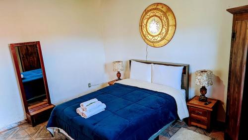 a bedroom with a blue bed and a mirror at Pouso de Santana in Tiradentes