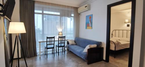 a living room with a blue couch and a bedroom at Batumi-Gonio First line Apartment in Gonio