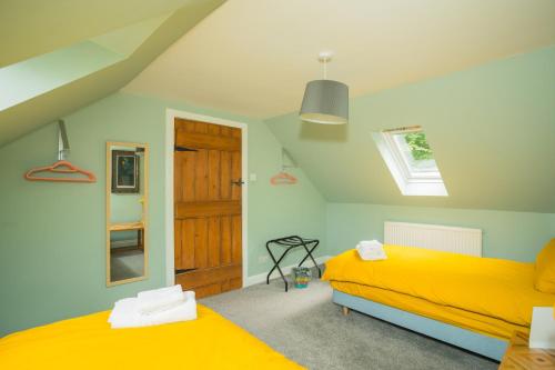a bedroom with two beds with yellow sheets and a door at Tig Cottage - a rural, quirky, pet friendly 2 bedroom cottage near Ballantrae in Ballantrae