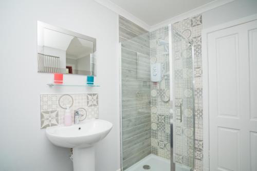 a white bathroom with a sink and a shower at Tig Cottage - a rural, quirky, pet friendly 2 bedroom cottage near Ballantrae in Ballantrae