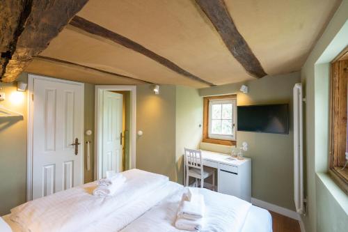 a bedroom with a bed with white sheets and a desk at Boutique-Hotel Stadtherberge Wetzlar in Wetzlar