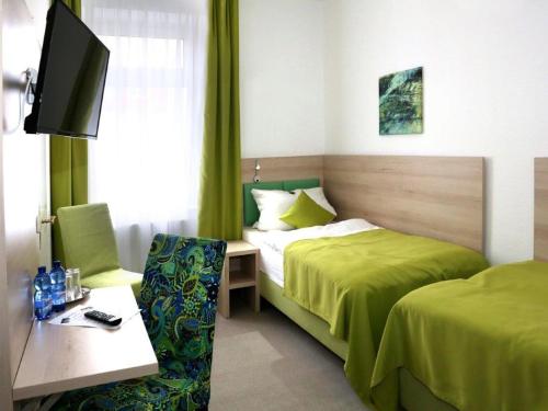 Habitación de hotel con 2 camas, escritorio y TV. en Arthotel, en Bad Pyrmont