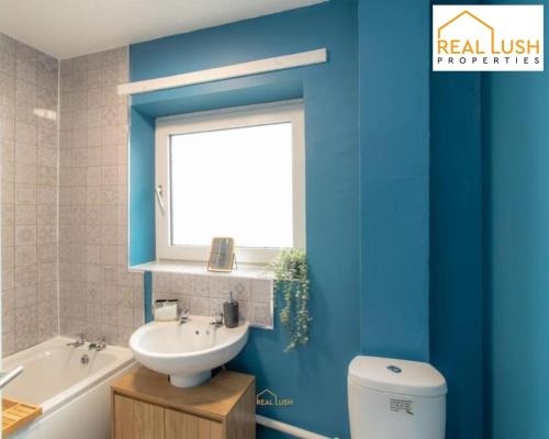 ein blaues Bad mit einem Waschbecken und einem WC in der Unterkunft HS2, NEC, And Airport Stay Home By Real Lush Properties - Three-Bedroom House In Birmingham, in Birmingham