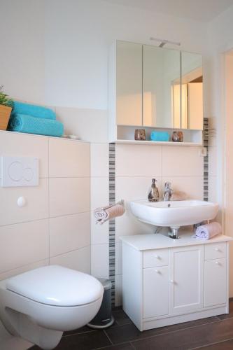 a white bathroom with a toilet and a sink at Ferienwohnung Helgoland in Dorum-Neufeld