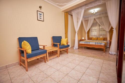 a living room with two chairs and a bed at The Forest House - Kawuku-Bunga in Kampala