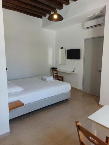 a white bedroom with a bed and a tv at Castellino Naxos in Naxos Chora