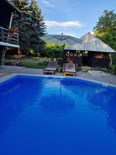 a large blue swimming pool with two chairs and an umbrella at Villa "Hipnotic" in Sarajevo