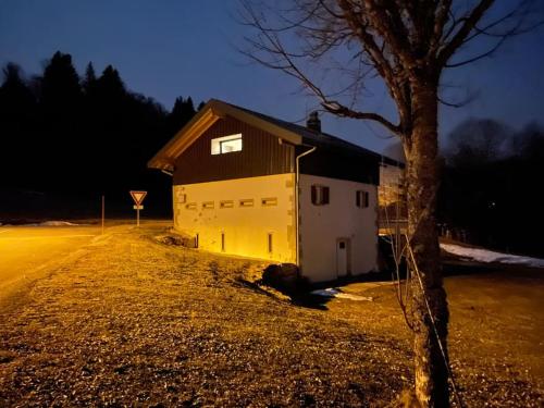 a barn sitting on the side of a road at night at GITE La fromagerie Haut Jura in La Mouille
