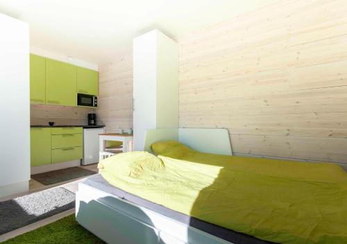 Cet appartement comprend une chambre avec un lit vert et une cuisine. dans l'établissement Yksiö Turun Hirvensalossa, à Turku