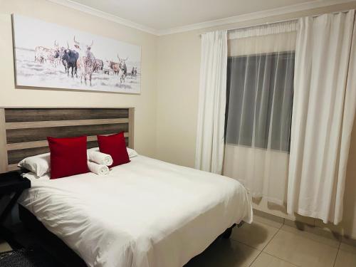 ein Schlafzimmer mit einem großen weißen Bett mit roten Kissen in der Unterkunft E & P Cave in Swakopmund