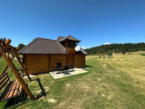 a log cabin in a field with some chairs at Apartmani nisicka oaza 2 in Ilijaš