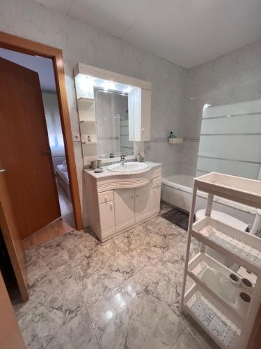 ein Badezimmer mit einem Waschbecken, einer Badewanne und einem Spiegel in der Unterkunft Ca La Noa 2 in Viladecáns