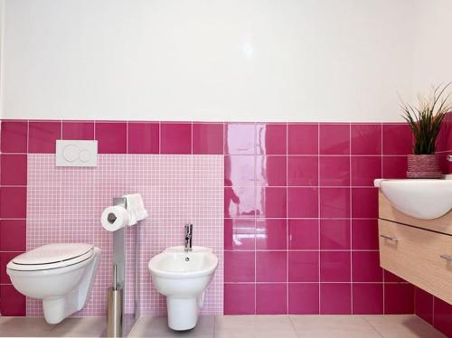een roze betegelde badkamer met een toilet en een wastafel bij casARCHÉ in Porto Torres