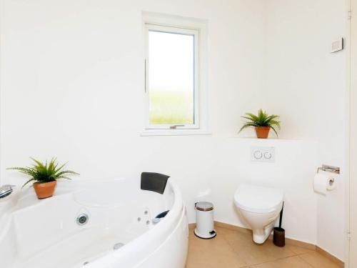 ein weißes Bad mit einer Badewanne und einem WC in der Unterkunft Captivating Holiday home in L kken with Whirlpool in Løkken