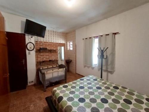a bedroom with a bed and a tv on the wall at Sitio em Santa Isabel Recanto da Tranquilidade in Santa Isabel