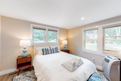 a bedroom with a large white bed with two windows at The Cape House in Cotuit