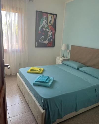 a bedroom with a bed with a blue blanket and a picture at Villetta Indipendente Sardegna in Villaputzu