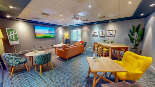 a waiting room with furniture and a flat screen tv at Holiday Inn Oxford by IHG in Oxford