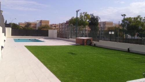 podwórko z zieloną trawą i basenem w obiekcie APART-DUPLEX-ATICO Tomares w mieście Tomares