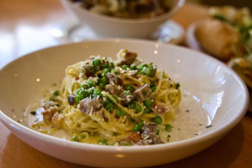 a white bowl of pasta with meat and green onions at Ashland Springs Hotel in Ashland
