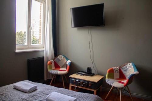 a room with two beds and two chairs and a tv at Open Doors Villa in Gdańsk