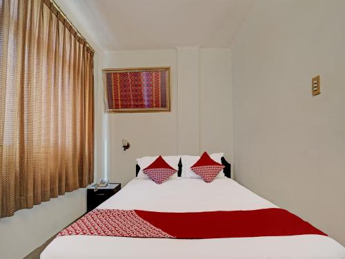 um quarto com uma cama vermelha e branca e uma janela em SUPER OYO 91805 Hotel Wisma Bari em Palimbão