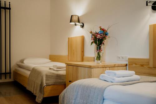 a room with two beds and a vase of flowers on a table at Bella Monte in Szczyrk