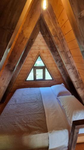 a large bed in a attic with a window at Bungaja Chalets in Shkodër