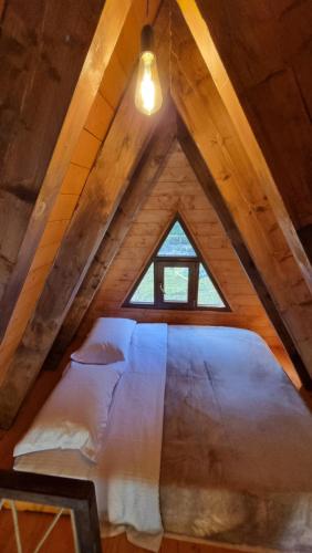 a bed in a attic with a window at Bungaja Chalets in Shkodër