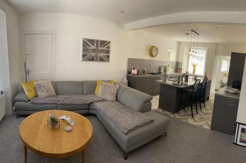 a living room with a couch and a table and a kitchen at Fantastic home in Brightons, Falkirk. in Polmont