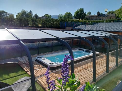 a hot tub on a deck with a roof at Hôtel L'Oustalet in Font-Romeu-Odeillo-Via