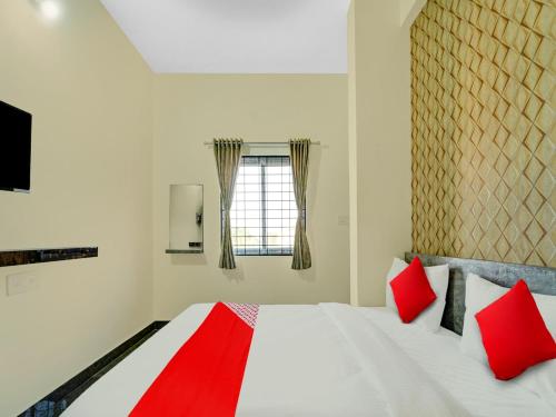 a bedroom with a bed with red pillows and a window at OYO Flagship Mathrushree Lodge in Yelahanka
