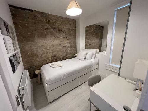 ein kleines Schlafzimmer mit einem Bett und einer Ziegelwand in der Unterkunft The Trinity College Townhouse in Dublin