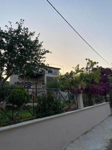 a white wall with a fence and trees and a building at villa kastanos in Amaliápoli