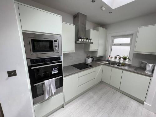 eine Küche mit weißen Schränken und Edelstahlgeräten in der Unterkunft The Trinity College Townhouse in Dublin