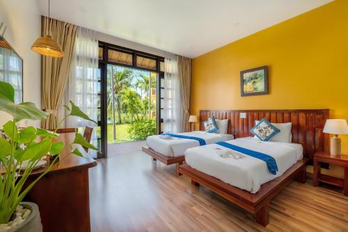 Duas camas num quarto com paredes amarelas em ZEN RETREAT HOI AN em Hoi An