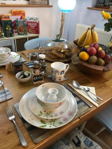 a wooden table with a bowl of fruit and a tea set at Blue Shutters in Weymouth