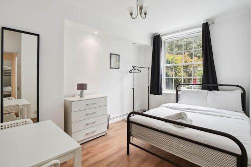 een witte slaapkamer met een bed en een raam bij APlaceToStay Central London Apartment, Waterloo (UPT) in Londen